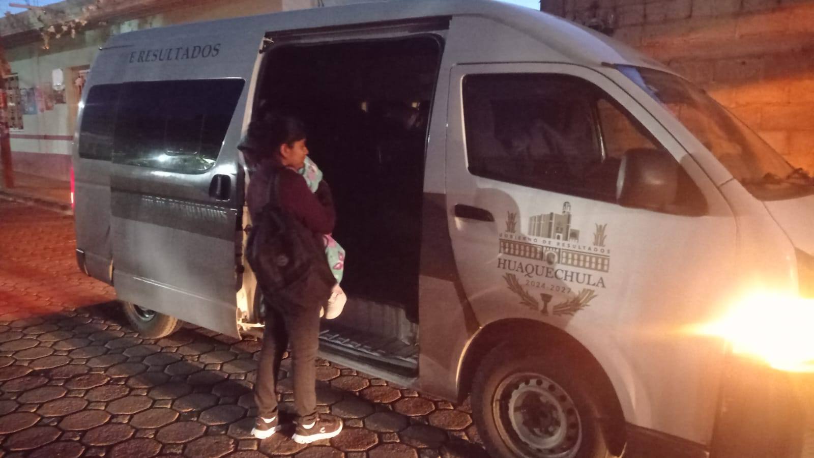 Mujer con un bebé en brazos aborda una camioneta oficial del Ayuntamiento de Huaquechula 2024-2027 durante la madrugada, como parte del programa gratuito de traslados médicos a hospitales de Puebla y Ciudad de México.