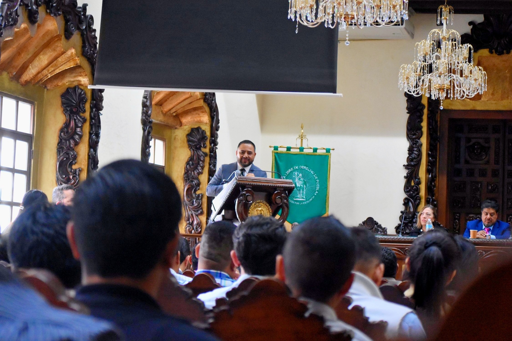 Un ponente expone en el Foro “Diálogos Universitarios sobre Migración” en la Escuela Libre de Derecho de Puebla, ante la presencia de estudiantes, académicos y representantes institucionales, incluido el Ayuntamiento de Huaquechula.