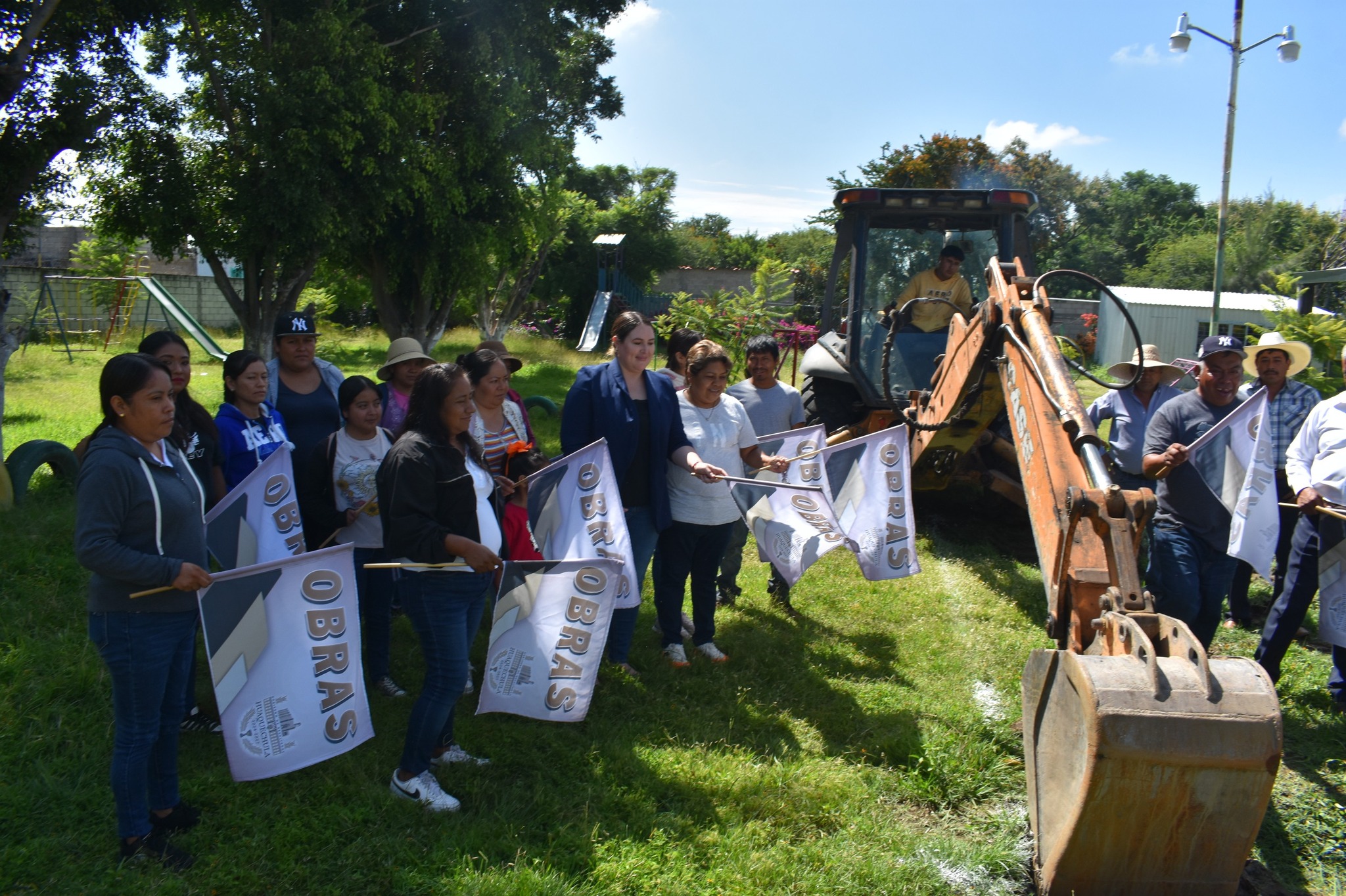 Habitantes y autoridades de Huaquechula dieron el banderazo de inicio de obra para la construcción de un módulo sanitario en el Jardín de Niños “Melchor Ocampo” en Soledad Morelos. Se observa maquinaria pesada y vecinos con banderas de obras municipales.
