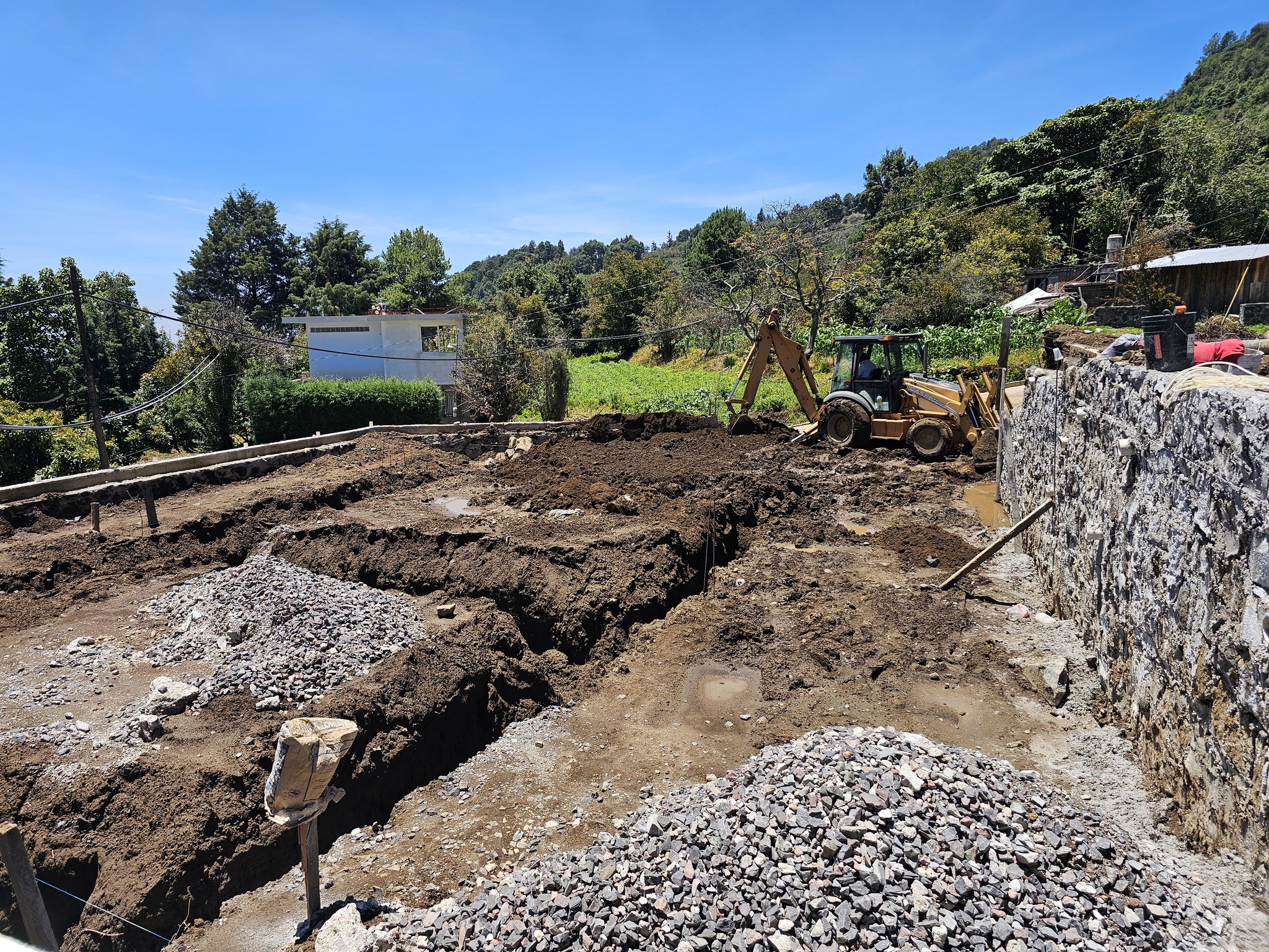 Terreno en proceso de construcción donde se observan trabajos de excavación y maquinaria pesada. Es parte de la obra de dos nuevas aulas didácticas en el Bachillerato Digital No. 175 de Santa Cruz Cuautomatitla, Tochimilco.