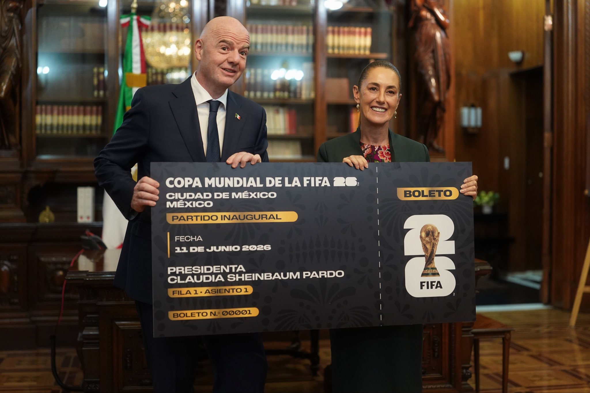 El presidente de la FIFA, Gianni Infantino, y la presidenta de México, Claudia Sheinbaum, sostienen un boleto simbólico de gran tamaño conmemorando el partido inaugural de la Copa Mundial 2026 en el Estadio Azteca.