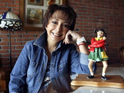 La actriz María Antonieta de las Nieves sonríe mientras posa junto a una figura de su icónico personaje “La Chilindrina”, símbolo de la televisión mexicana y la cultura popular latinoamericana.