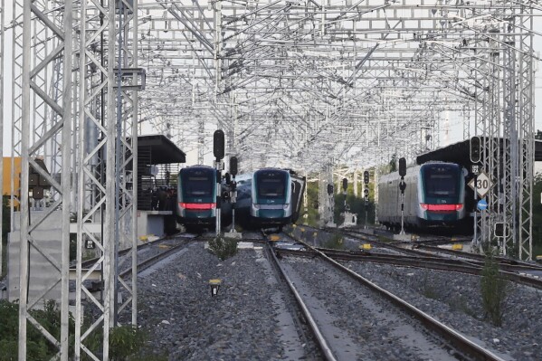 Tres vagones del Tren Maya se encuentran detenidos en una estación ferroviaria, bajo una estructura metálica de protección, tras el incidente ocurrido en Izamal, Yucatán.