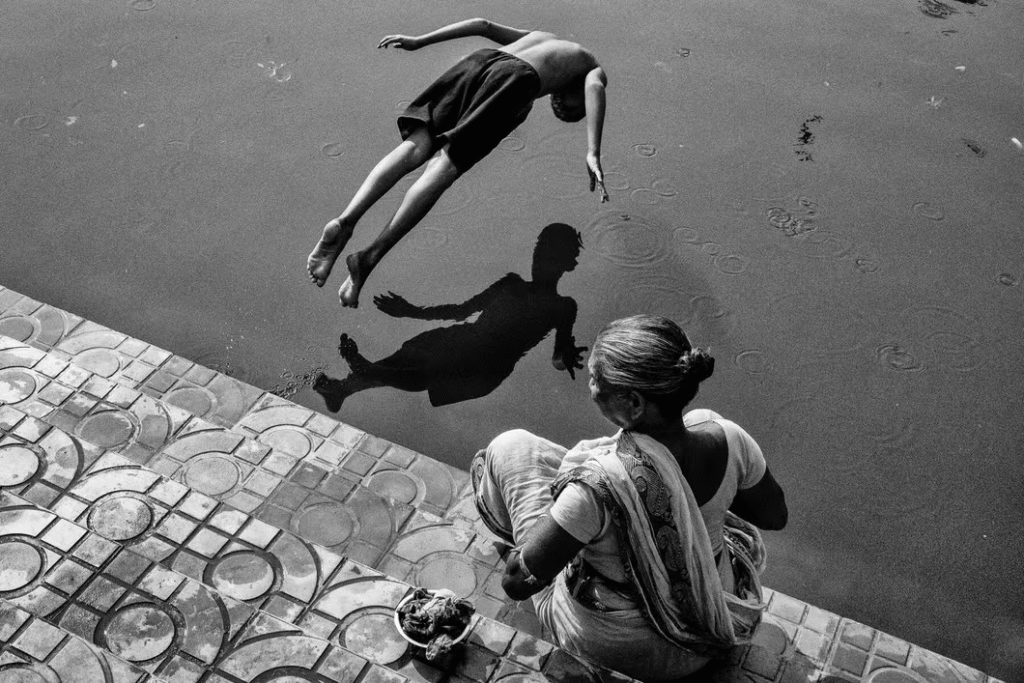 Premio Blanco y Negro Enero 2025: “Salto de fe”, una fotografía en blanco y negro tomada en Calcuta, India, por Subhran Karmakar. Inmortaliza un instante mágico de un niño saltando sobre un reflejo ondulante .