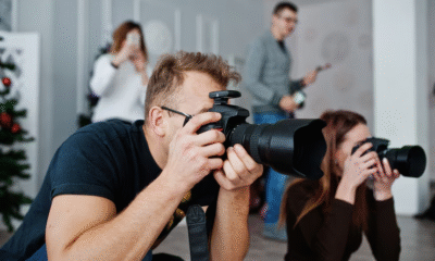 Grupo de fotógrafos capturando imágenes con cámaras profesionales durante una sesión en interiores.
