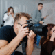 Grupo de fotógrafos capturando imágenes con cámaras profesionales durante una sesión en interiores.