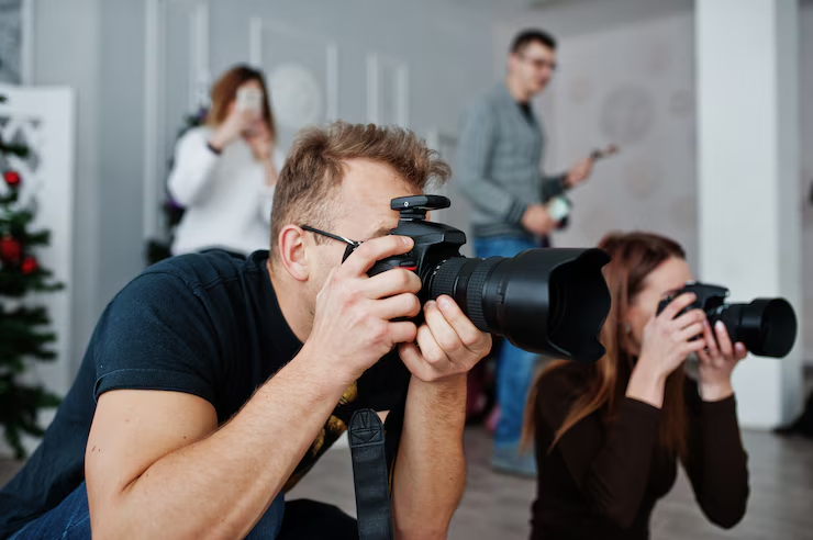 Grupo de fotógrafos capturando imágenes con cámaras profesionales durante una sesión en interiores.