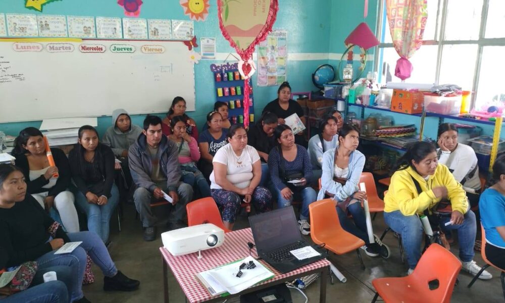 Grupo de madres y padres de familia reunidos en un salón de clases, participando en una plática impartida por el Ayuntamiento de Huaquechula sobre prevención del maltrato y abuso sexual infantil.