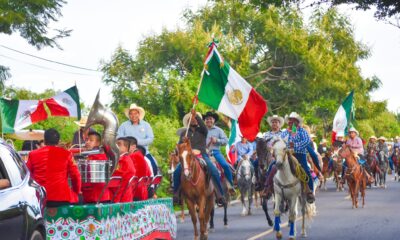 Jinetes a caballo, acompañados por una banda musical y portando banderas de México, participan en la cabalgata organizada por el Ayuntamiento de Huaquechula para conmemorar el 215 aniversario de la Independencia.