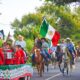 Jinetes a caballo, acompañados por una banda musical y portando banderas de México, participan en la cabalgata organizada por el Ayuntamiento de Huaquechula para conmemorar el 215 aniversario de la Independencia.