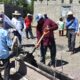 Un grupo de habitantes y autoridades municipales participa en el arranque de la obra de adoquinamiento en la calle Cuauhtémoc, en La Soledad Morelos, Huaquechula. Un hombre vierte mezcla de cemento con pala mientras la comunidad observa.