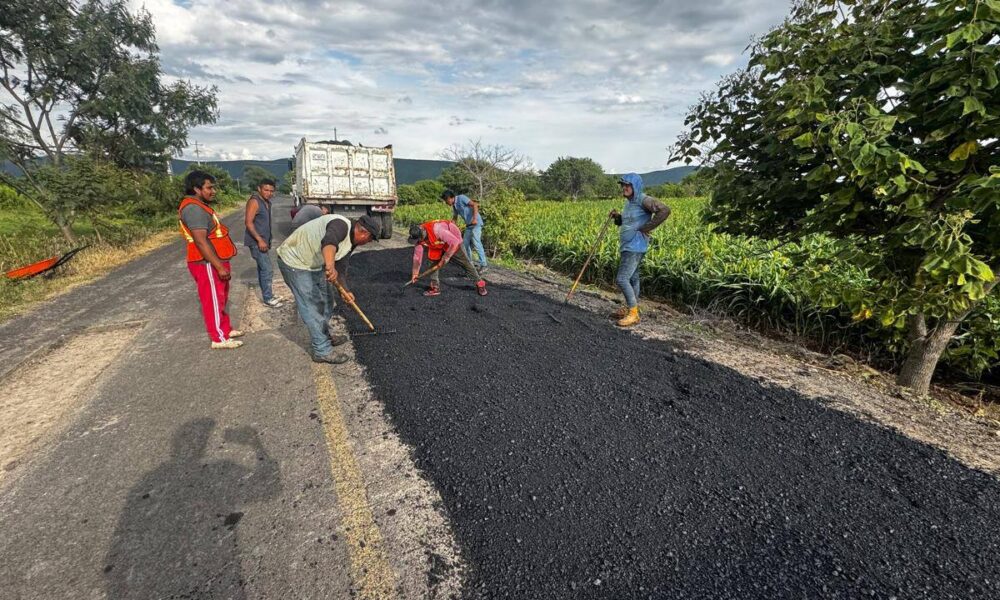 Cuadrilla de trabajadores del Ayuntamiento de Huaquechula realizando labores de bacheo en carretera rural, extendiendo mezcla asfáltica para mejorar la seguridad vial en el tramo Teacalco–Cuauhtémoc.