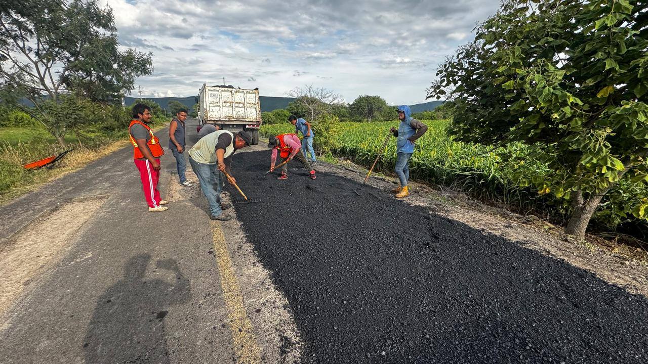 Cuadrilla de trabajadores del Ayuntamiento de Huaquechula realizando labores de bacheo en carretera rural, extendiendo mezcla asfáltica para mejorar la seguridad vial en el tramo Teacalco–Cuauhtémoc.