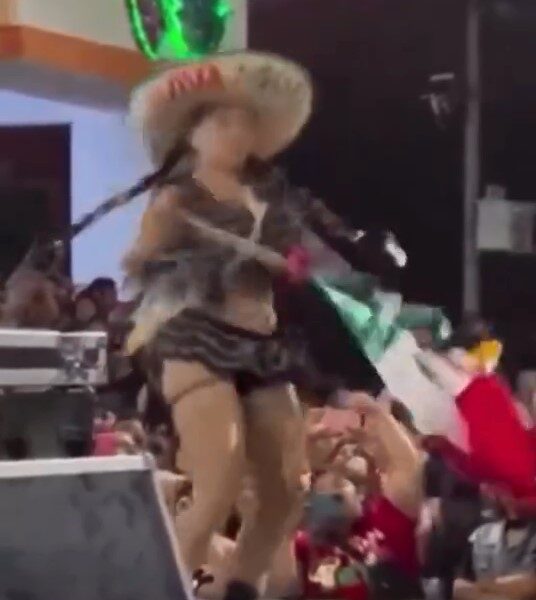 Bailarina en escenario durante festejos del Grito de Independencia en Reforma, Chiapas, usando la bandera nacional como parte de un show exótico frente al público.