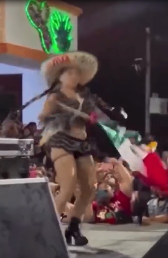 Bailarina en escenario durante festejos del Grito de Independencia en Reforma, Chiapas, usando la bandera nacional como parte de un show exótico frente al público.