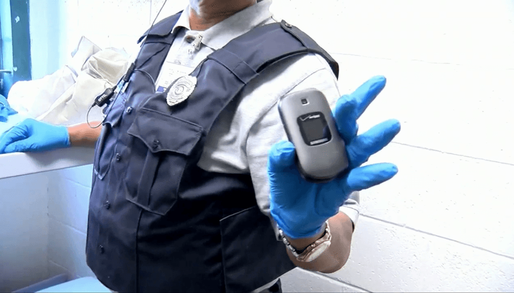 Un agente de seguridad muestra un teléfono celular decomisado en un penal, evidencia del hallazgo tras la activación de la alerta sísmica durante el Simulacro Nacional 2025 en México.