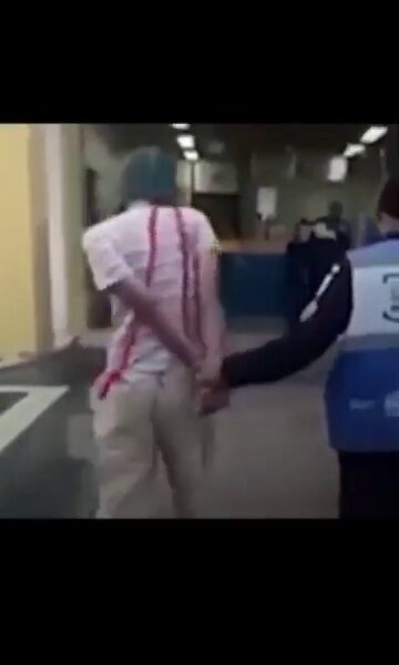 Joven disfrazado de El Chavo del 8 es escoltado esposado por un agente de seguridad durante un operativo en Río de Janeiro, Brasil.