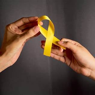 Dos manos sostienen un lazo amarillo, símbolo de esperanza y apoyo en la prevención del suicidio.