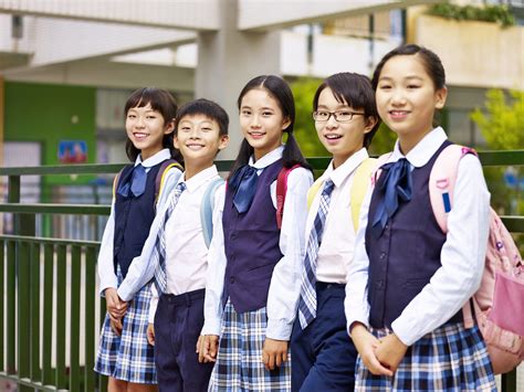 Niños japoneses en uniforme escolar posan frente a su escuela, reflejando la educación moral, el respeto y los valores del sistema educativo en Japón.