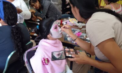 Mujer maquillando a niña en el Taller de Autoempleo de Maquillaje Artístico del DIF Municipal Tochimilco, con temática del Día de Muertos.