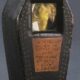 Pequeño ataúd de madera con una ventana que muestra a un canario embalsamado, identificado como “Little Joe”, símbolo histórico de la minería del siglo XIX.
