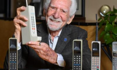 Inventor sosteniendo el primer teléfono celular Motorola DynaTAC 8000X, símbolo del inicio de la comunicación móvil moderna y de la innovación tecnológica.