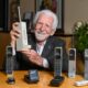 Inventor sosteniendo el primer teléfono celular Motorola DynaTAC 8000X, símbolo del inicio de la comunicación móvil moderna y de la innovación tecnológica.