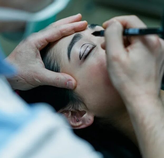 Médico dibujando líneas de guía sobre el párpado de una mujer antes de una cirugía estética en Corea del Sur.