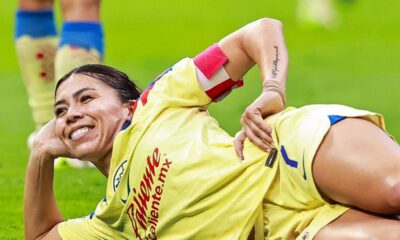 Kiana Palacios celebra en el césped tras anotar un gol con el Club América Femenil, vistiendo el uniforme amarillo del equipo.