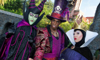 La Reina Malvada de Blancanieves con su icónica corona y capa en una escena de los parques de Disney.