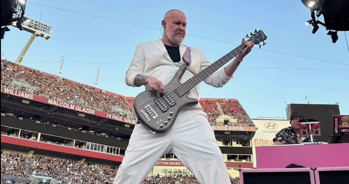 Sam Rivers, bajista de Limp Bizkit, tocando en vivo con su bajo en un estadio lleno de público durante una presentación de la banda.