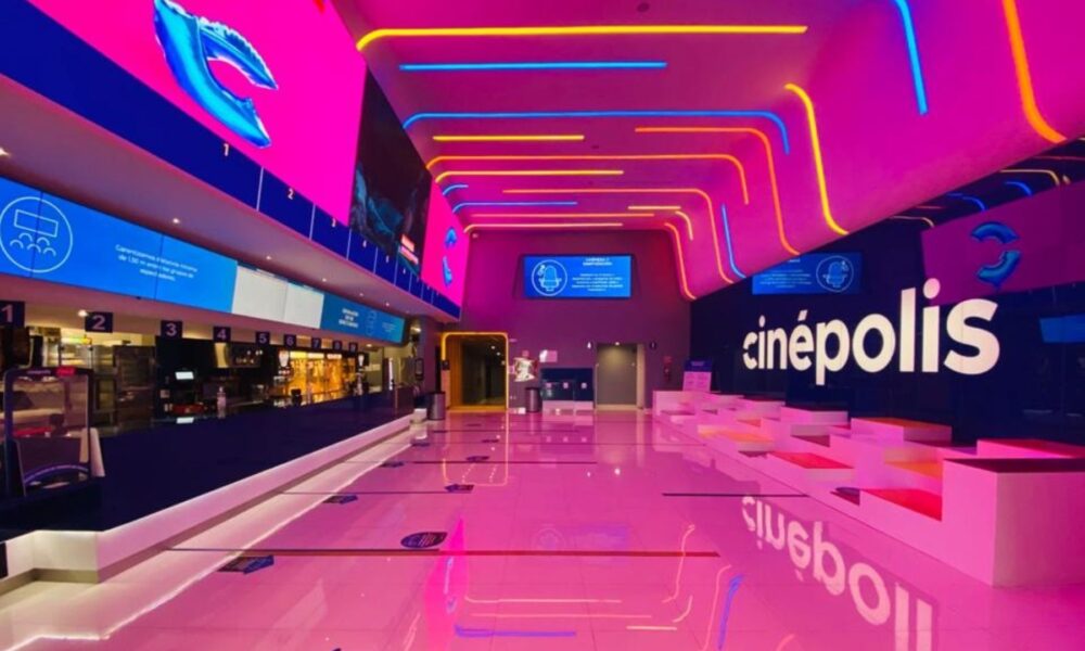 Interior de una sala de Cinépolis iluminada con luces de neón en colores rosa, azul y amarillo, representando la promoción de boletos a 29 pesos.