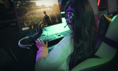 Mujer gamer utilizando computadora en un entorno de videojuegos, representando el crecimiento del 48% de mujeres en la industria del gaming a nivel mundial.