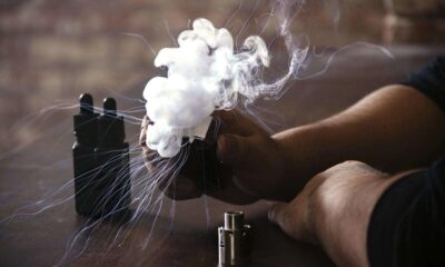 Silueta de una persona vapeando mientras una gran nube de vapor sale del dispositivo.