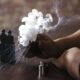 Silueta de una persona vapeando mientras una gran nube de vapor sale del dispositivo.
