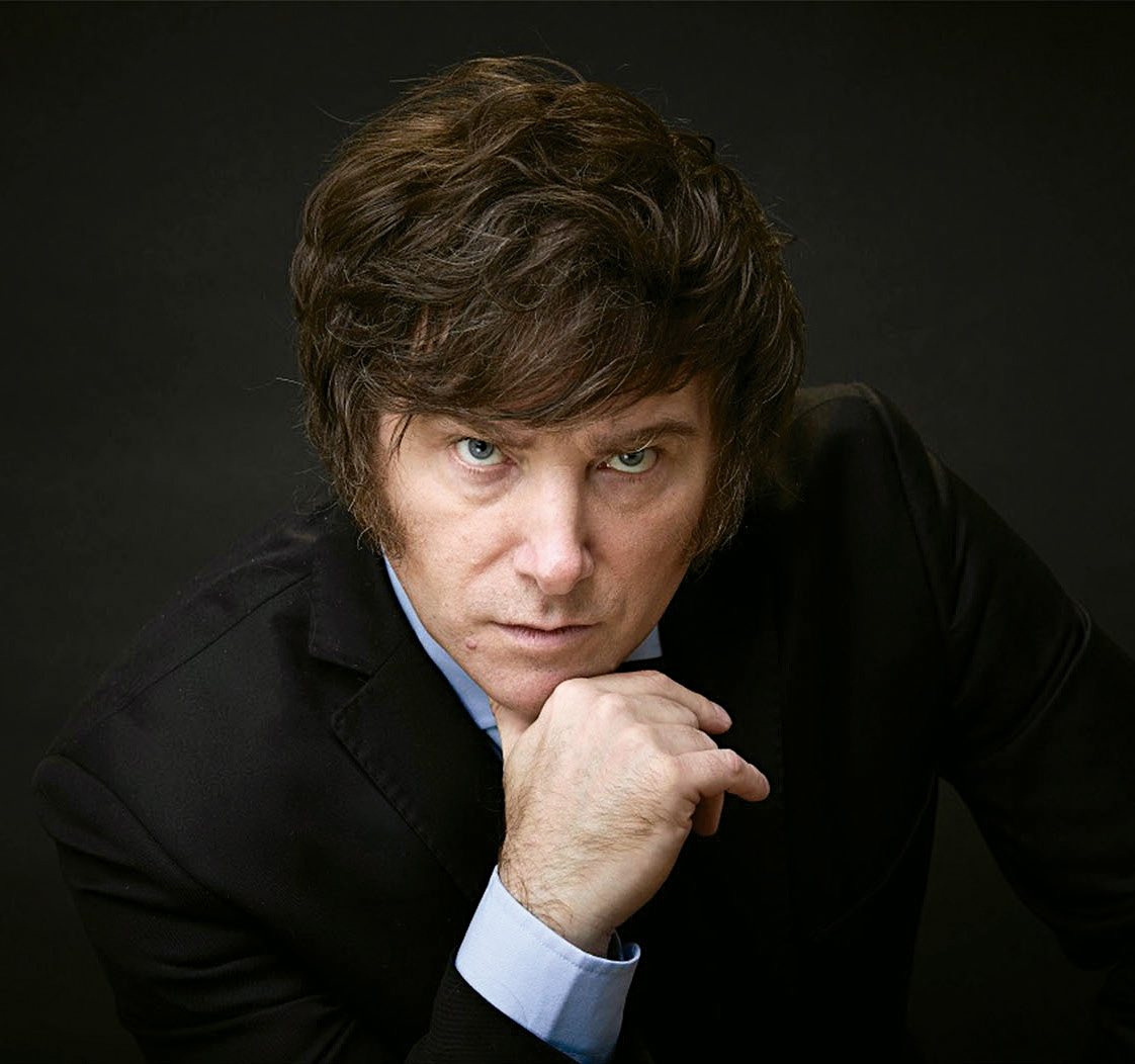 Retrato serio del presidente argentino Javier Milei, posando con traje formal, mano en el mentón y fondo oscuro.