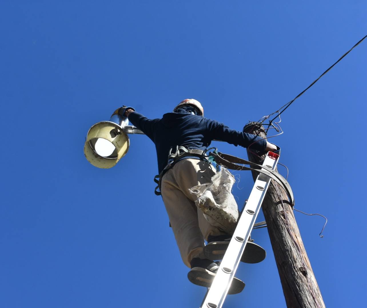 Trabajador realiza mantenimiento a una luminaria en Huaquechula como parte del programa de alumbrado público en San Juan Huiluco y San Diego El Organal.