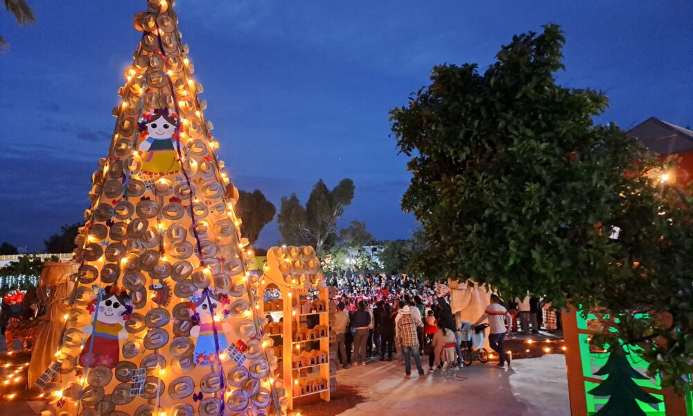 Nacimiento Monumental Artesanal iluminado por la noche, construido con materiales tradicionales en la cabecera municipal de Huaquechula, con visitantes reunidos alrededor.