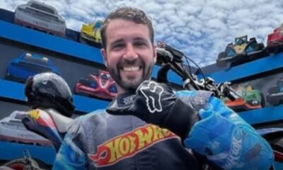 Piloto profesional vestido con traje de Hot Wheels sonriendo antes de realizar acrobacias en motocicleta.