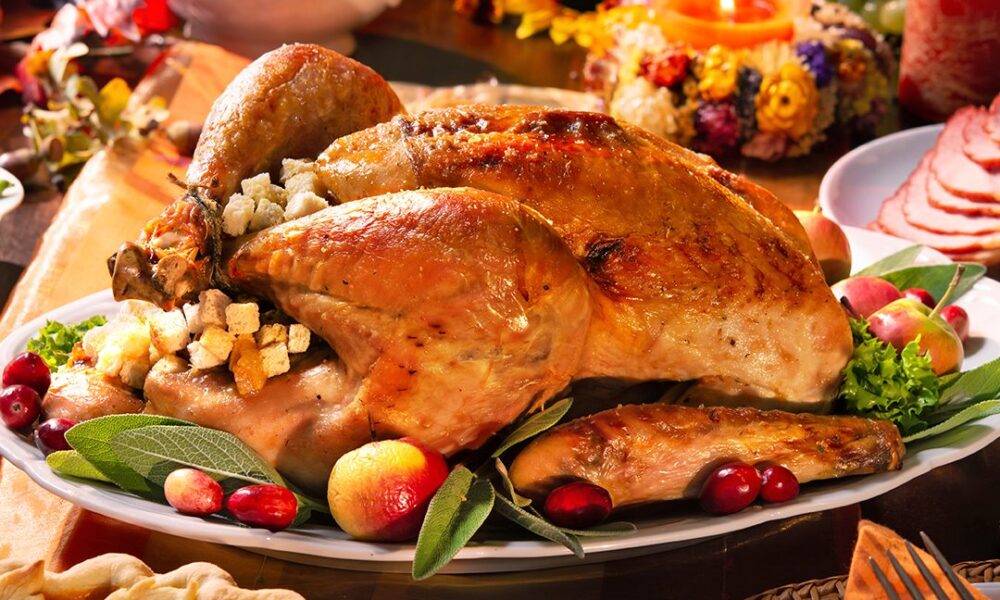 Persona sirviendo pavo en una mesa con velas durante una cena de Thanksgiving o Acción de Gracias.