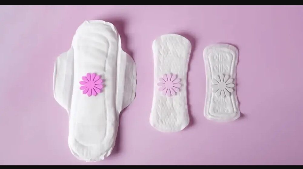 Tres toallas sanitarias sobre fondo rosa, representando la innovación tecnológica MenstruAI que analiza la sangre menstrual para detectar enfermedades.