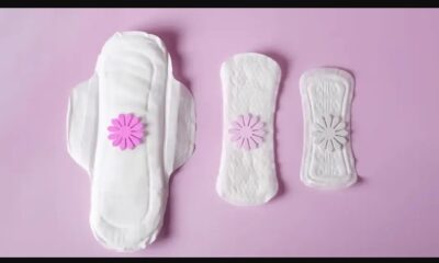 Tres toallas sanitarias sobre fondo rosa, representando la innovación tecnológica MenstruAI que analiza la sangre menstrual para detectar enfermedades.