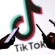 Tres personas sostienen teléfonos inteligentes frente al logo de TikTok, en un ambiente oscuro que resalta el uso constante de la plataforma.
