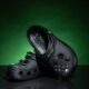 Crocs color negro edición especial inspirados en Xbox, con botones y diseño similar al control de la consola, sobre fondo verde oscuro.