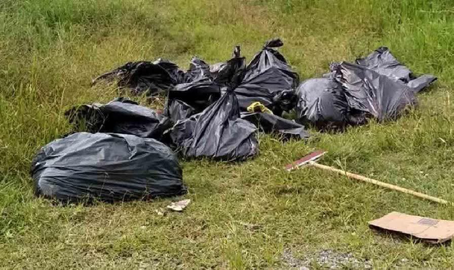 Bolsas negras colocadas en la orilla de un terreno con pasto, donde se presume hay restos humanos, relacionadas con hallazgos recientes en Zapopan, Jalisco.