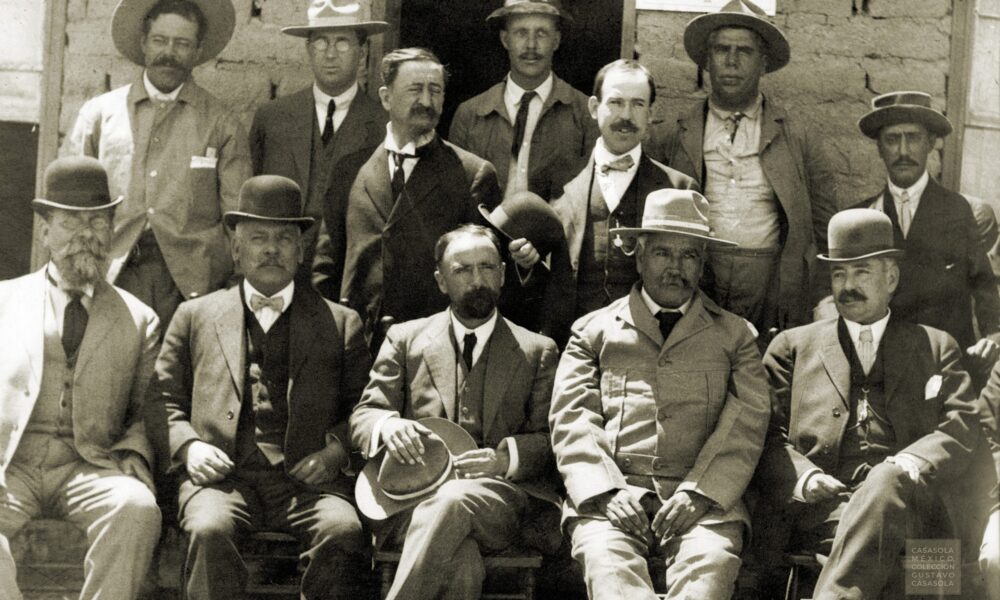 Histórica fotografía en blanco y negro de Francisco I. Madero acompañado de hombres revolucionarios durante el contexto de la Revolución Mexicana.