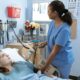 Enfermera atendiendo a una paciente joven en una cama de hospital, sosteniendo una barra de control médico en una habitación equipada.