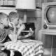 Dos niños observando atentos un televisor antiguo en blanco y negro mientras comen, representando la nostalgia y el impacto histórico de la televisión en la vida cotidiana.