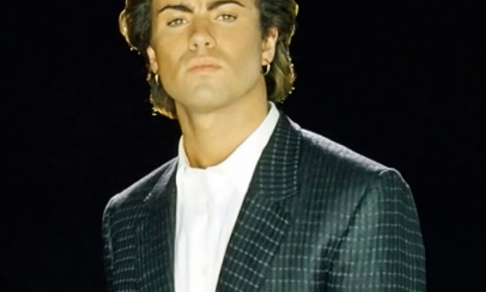 Fotografía del cantante británico George Michael con traje oscuro en fondo negro