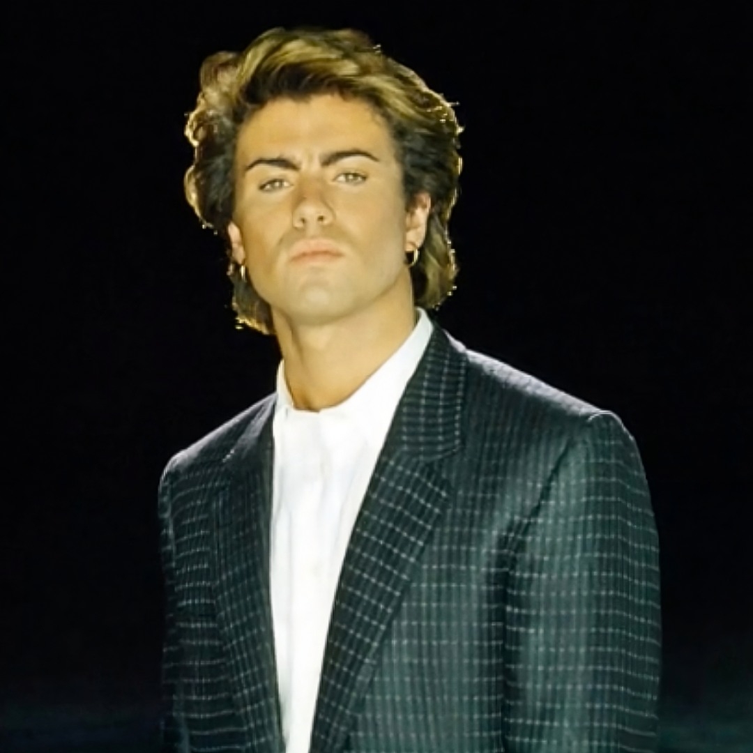 Fotografía del cantante británico George Michael con traje oscuro en fondo negro